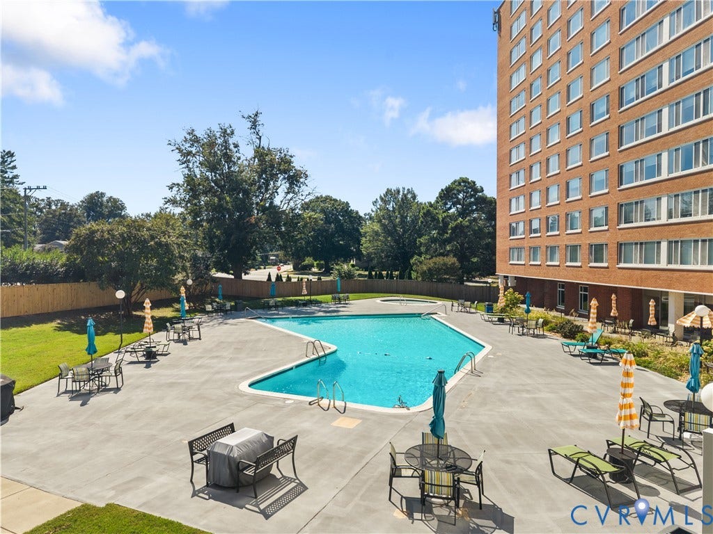 Expansive outdoor pool with integrated spa, surrounded by a concrete patio, and mature landscaping