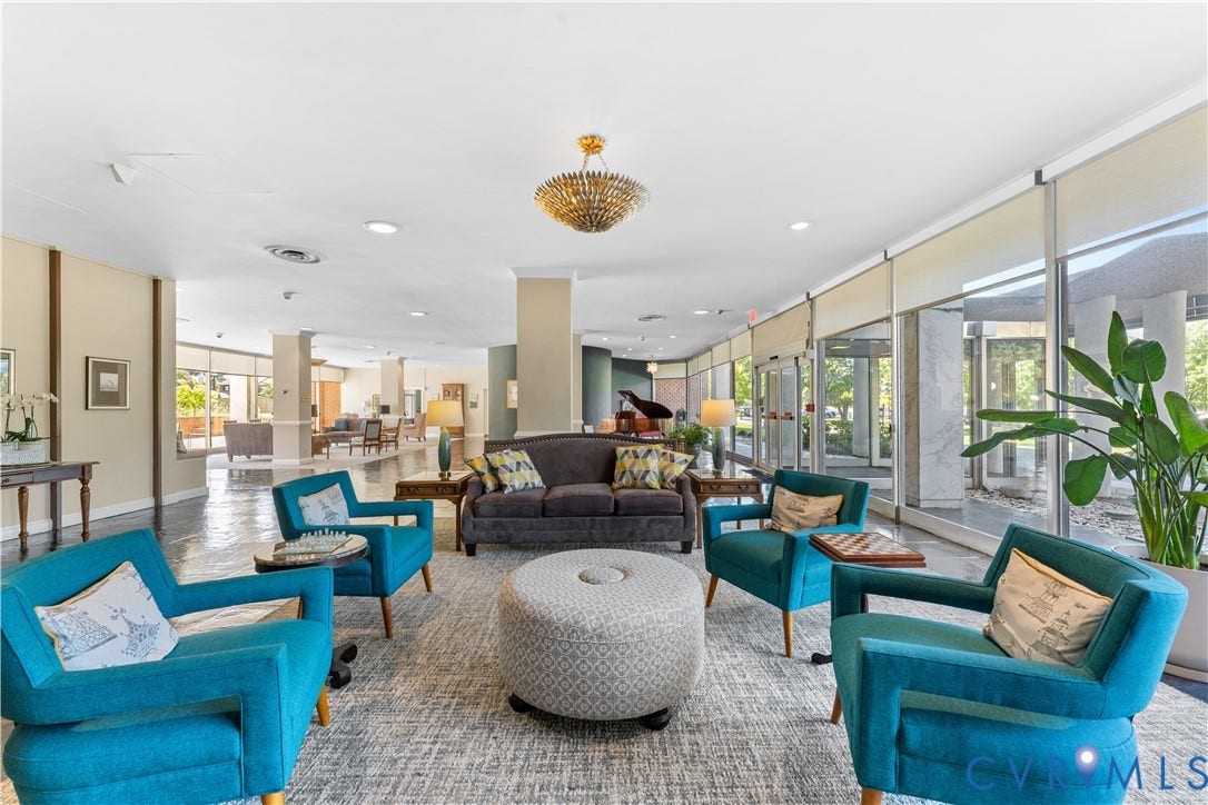 Spacious common area featuring a decorative chandelier, ample natural light, and a grand piano