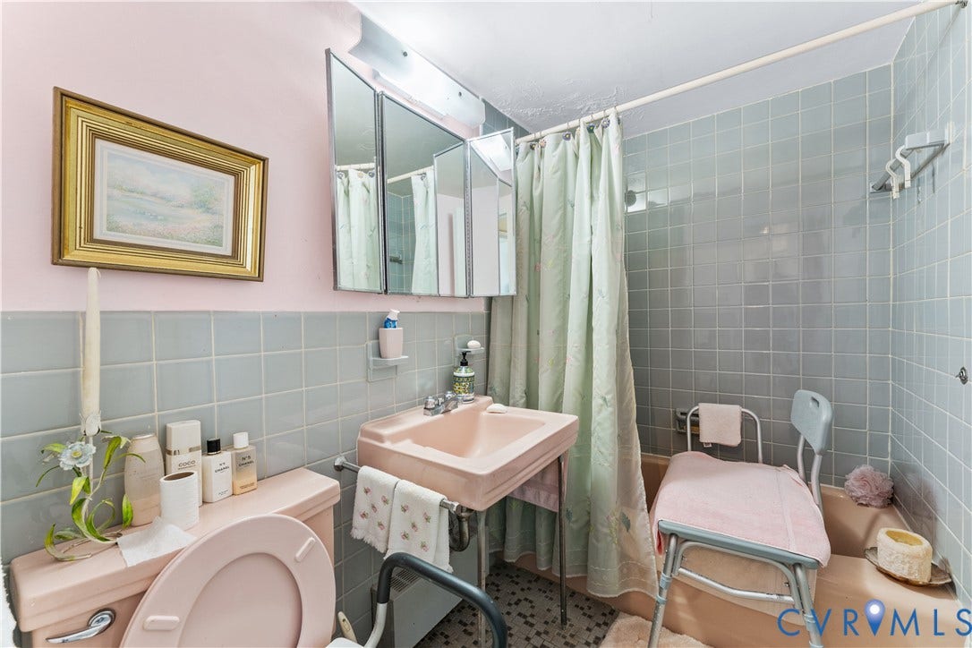 Bathroom featuring a three-panel mirrored medicine cabinet, a wall-mounted sink, and light blue wall tiling