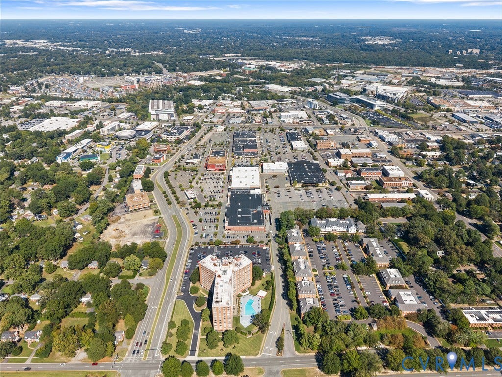 Aerial perspective of a developed urban area featuring diverse building types and extensive tree canopy