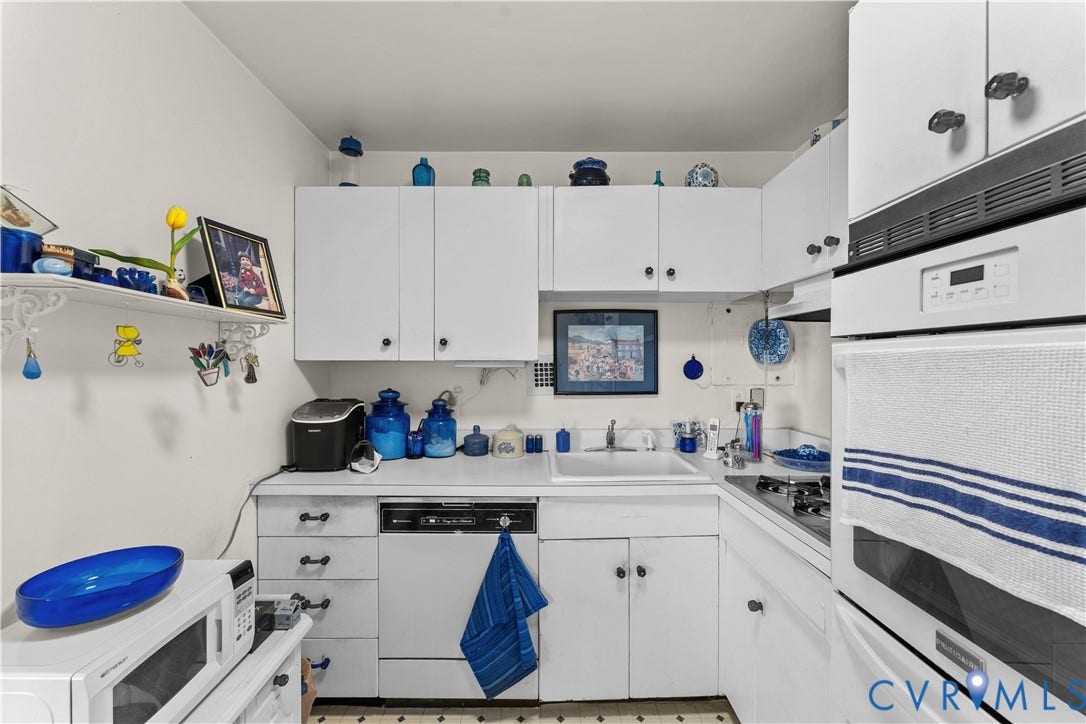 White cabinetry, built-in wall oven, under-cabinet lighting, and a neutral countertop