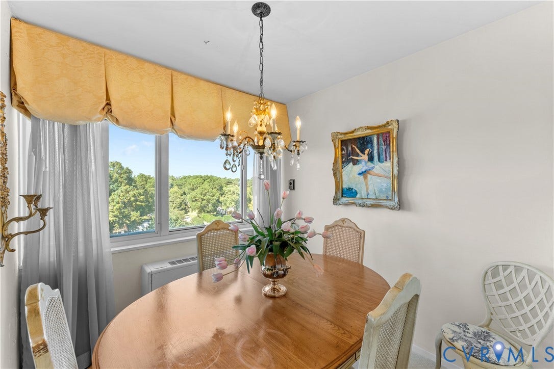 Window with a decorative valance and sheer curtains, featuring a chandelier with crystal accents, and light wall finishes