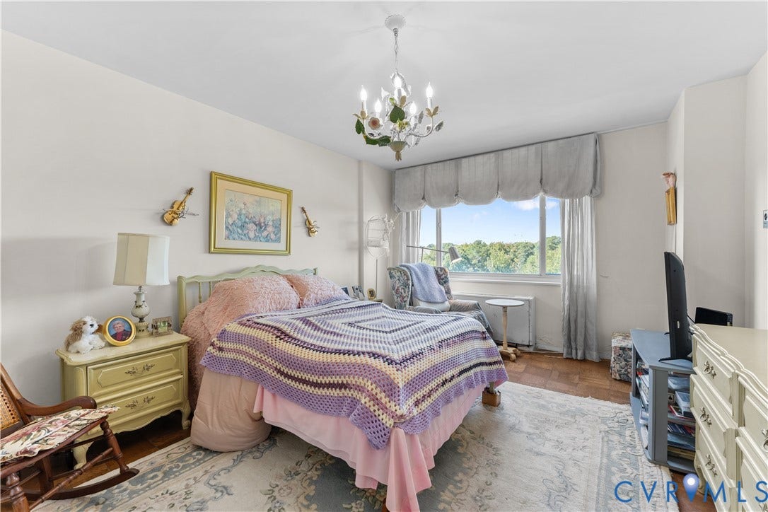 Hardwood flooring, chandelier lighting, expansive window, built-in air conditioning unit, and painted walls