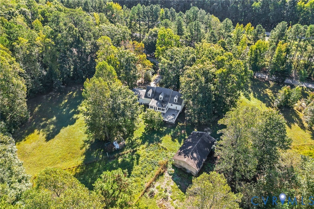 Expansive tree-lined property featuring a colonial-style residence, a detached auxiliary structure, and substantial green spaces