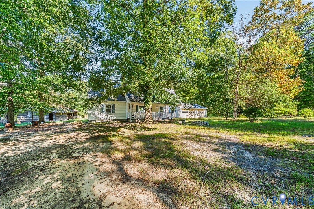 Mature trees providing shade, a white exterior, and a covered front porch, with an attached garage
