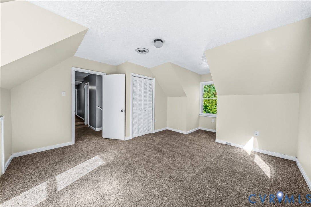 Carpeted room featuring a single window, white trim, and a bi-fold closet door