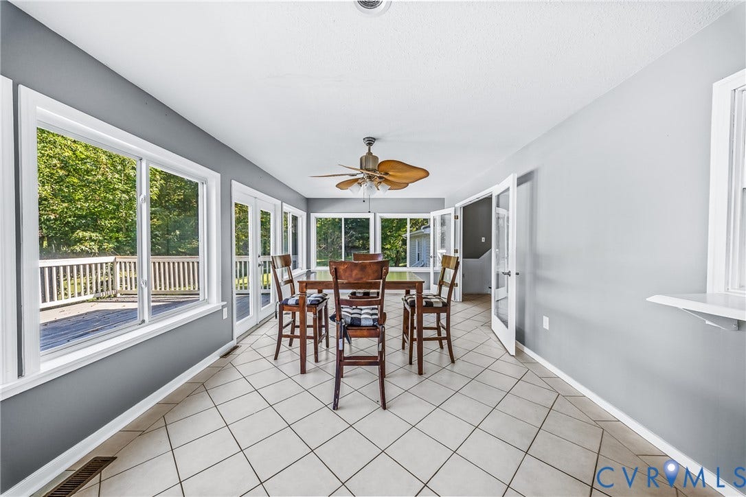 Spacious room featuring neutral tile flooring, multiple sets of French doors, and a ceiling fan