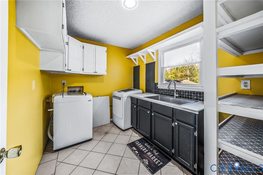 White cabinetry, black lower cabinets, dual basin sink, window, and built-in shelving