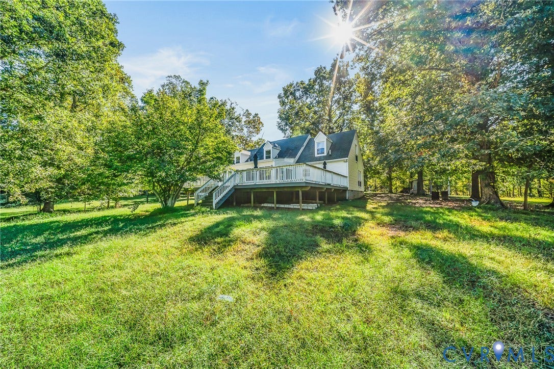 Expansive natural landscape with mature trees and a multi-level rear deck