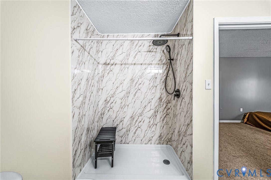 Shower stall with marble-look wall panels and a white shower base