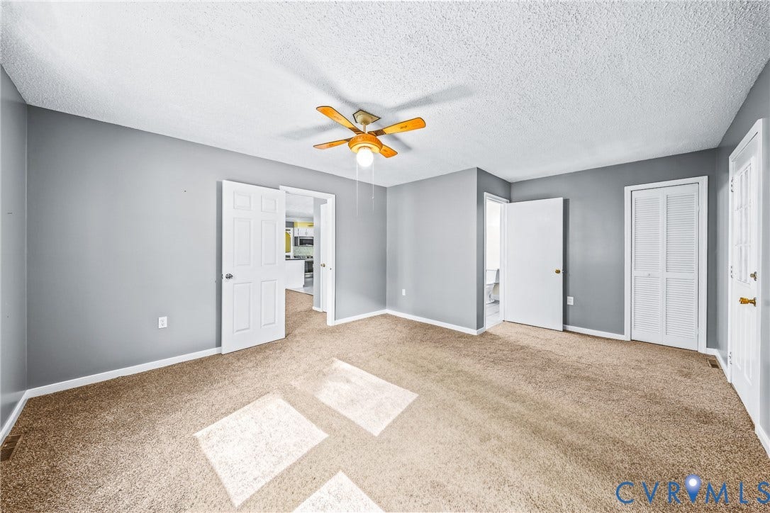 Carpeted room with a ceiling fan, light gray painted walls, white trim, and multiple white paneled doors