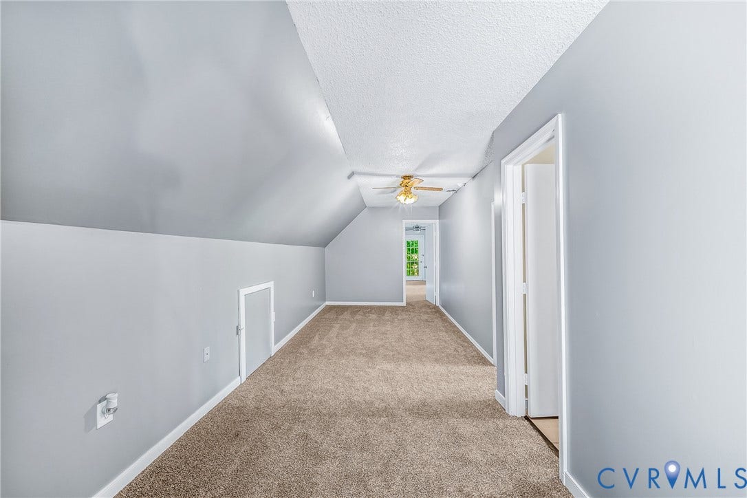 Carpeted flooring, sloped ceiling, attic access panel, and ceiling fan with lighting