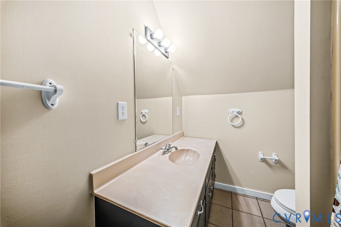 Vanity with integrated sink and countertop, wall-mounted mirror, and tile flooring