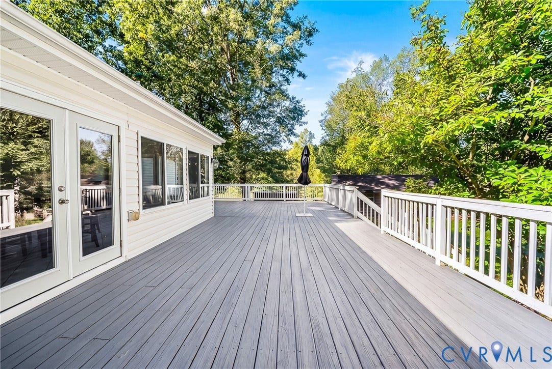 Expansive outdoor deck with white railing, glass French doors, and exterior siding