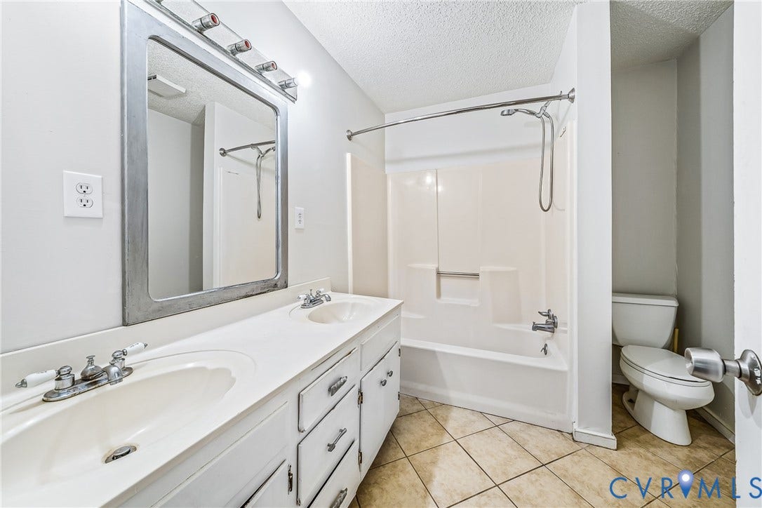 Double vanity with integrated sinks, framed mirror, and tile flooring