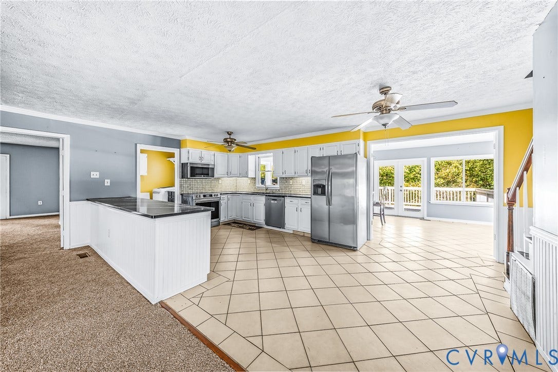 Spacious kitchen featuring white cabinetry, stainless steel appliances, and tile flooring