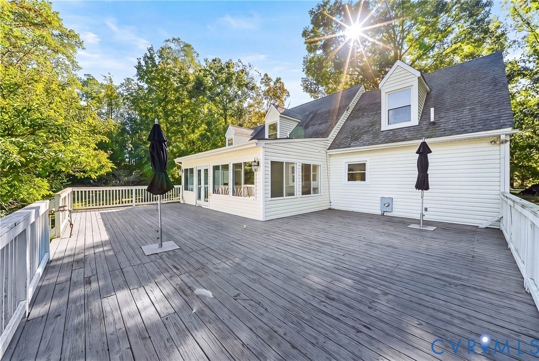 Expansive deck with white railings, a screened-in porch with multiple windows, white siding, and a dark shingle roof with dormer windows