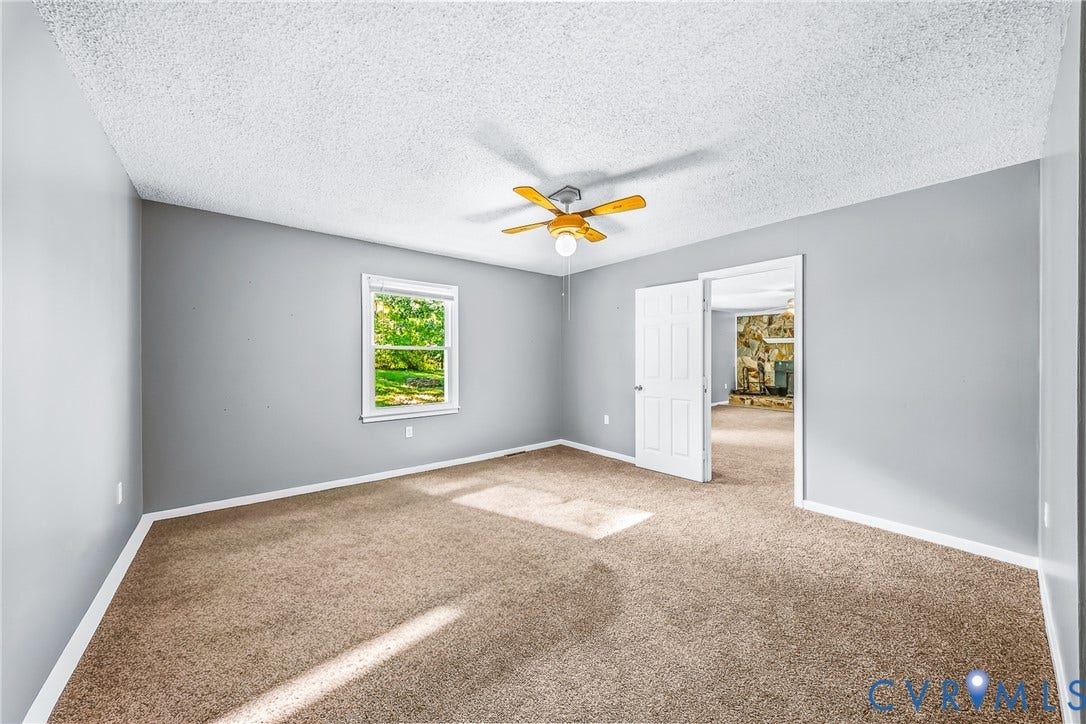 Carpeted flooring, neutral wall tones, ceiling fan with integrated lighting, and a white paneled door