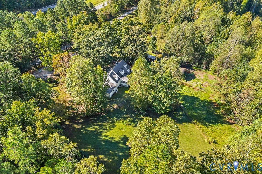 Expansive property featuring a gabled roofline, multiple dormer windows, and a surrounding tree canopy
