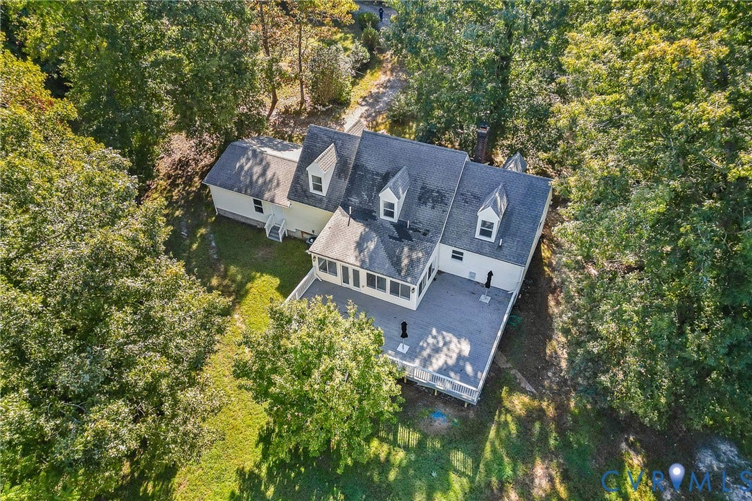 Multi-level roofline with three dormer windows, surrounded by mature trees