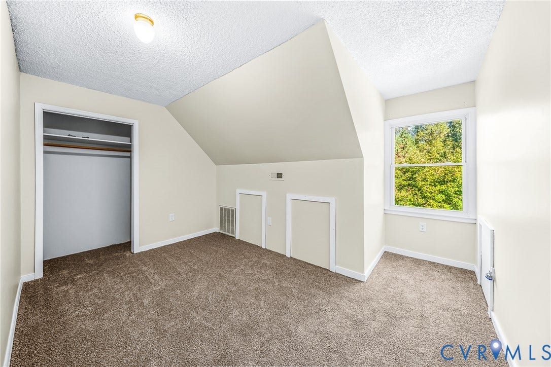 Carpeted room featuring a single window, a built-in closet with hanging rods, and sloped ceiling