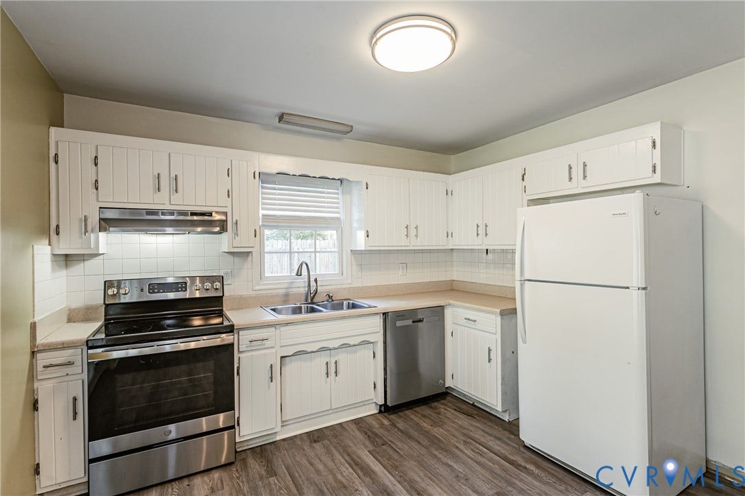Kitchen featuring wood-finish flooring, white cabinetry, a stainless steel range, and a dual basin sink