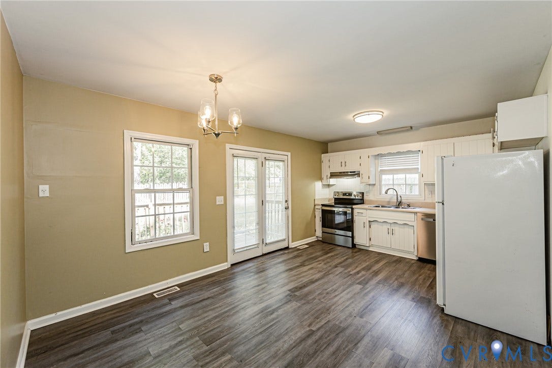 Kitchen featuring white cabinetry, stainless steel appliances, and wood-finish flooring