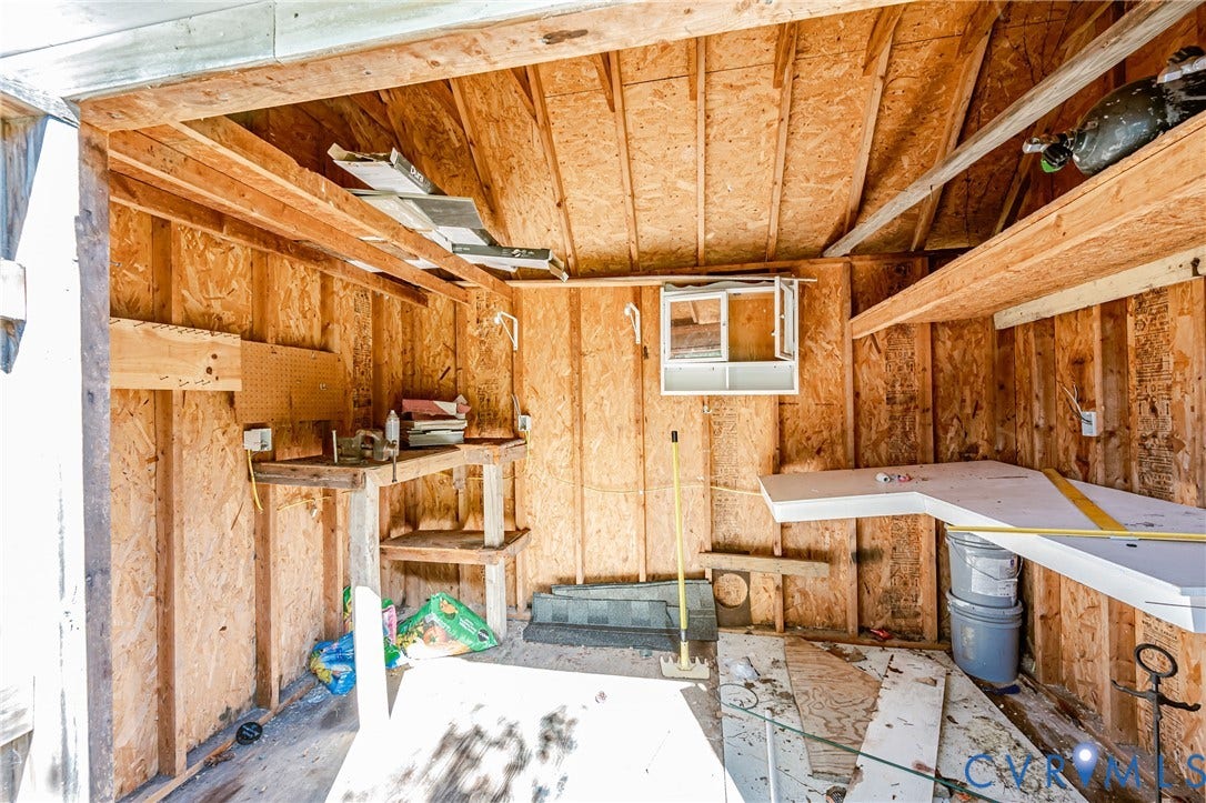 Utility structure with exposed wood framing, built-in shelving, and a single window