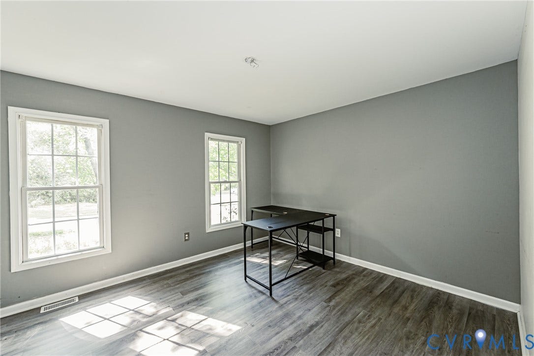 1st floor bedroom #2 Wood-finish flooring, two large windows, white trim, and neutral gray walls