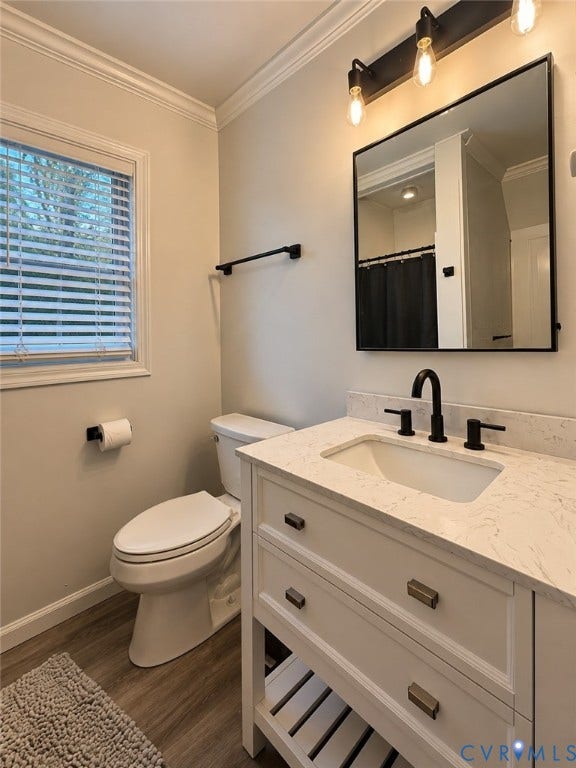 Bathroom featuring a white vanity with a white countertop and integrated sink, matte black faucet, and wood-finish flooring
