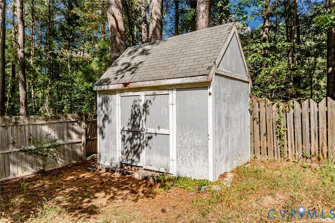 Storage shed with double doors, pitched roof, and wood fencing