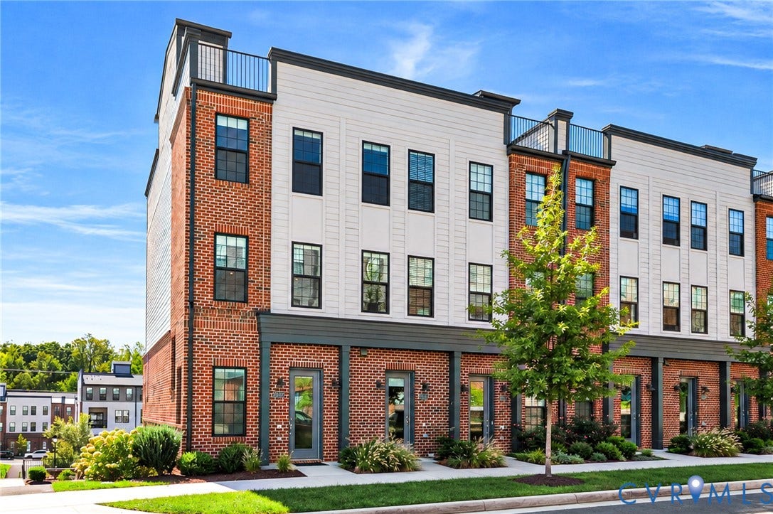 Brick and siding exterior with multiple balconies, black-framed windows, and integrated landscaping