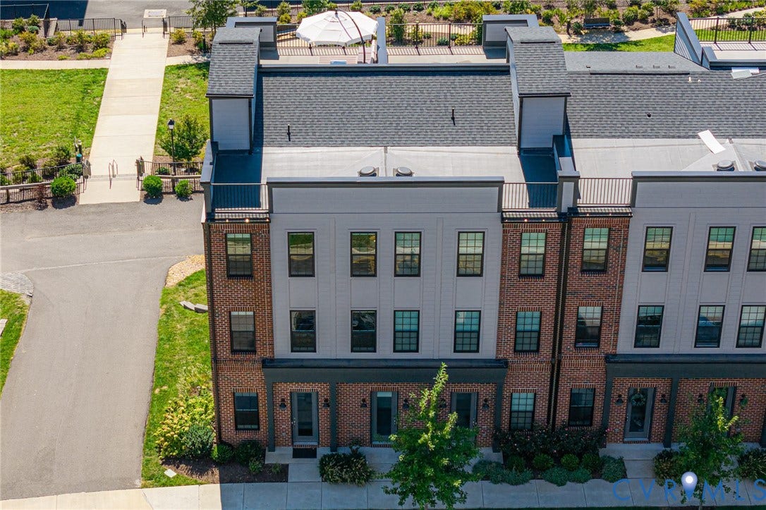 Brick and siding exterior, multi-story structure, flat roof, roof deck with white umbrella, paved walkway