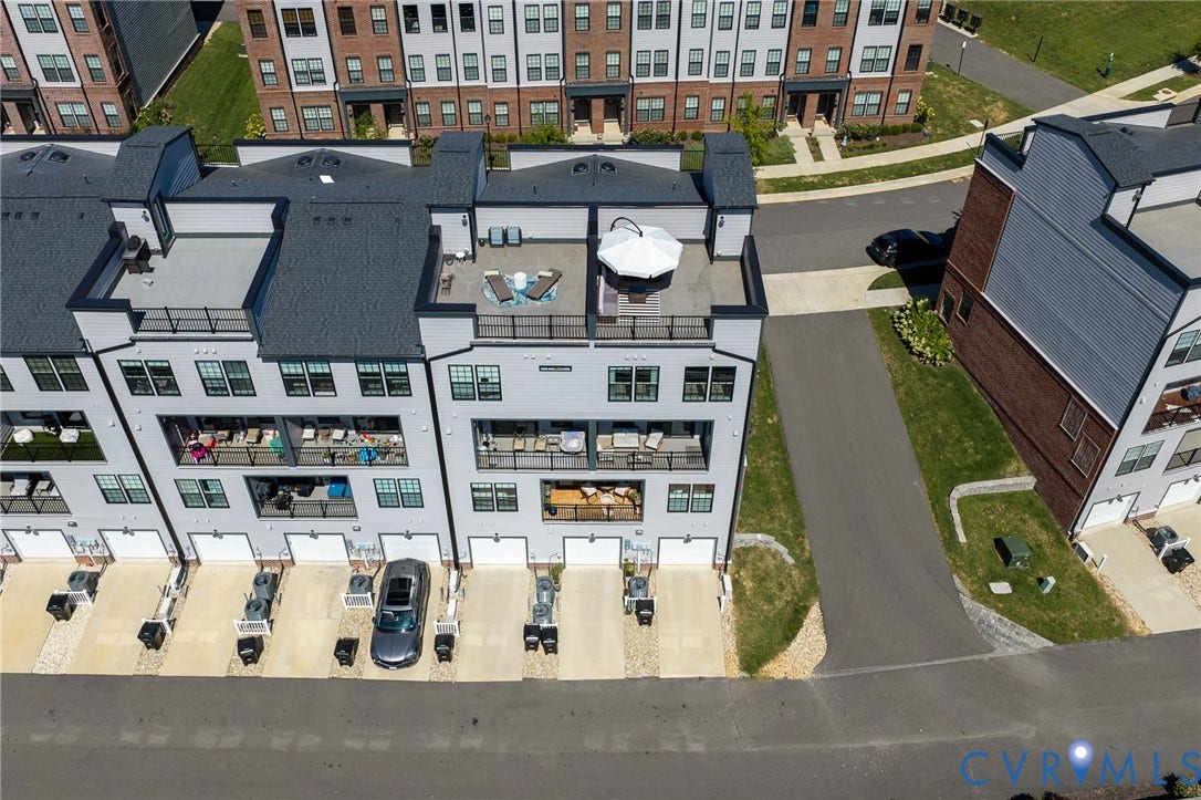 Multistory townhouse with rooftop terrace, multiple balconies, individual garage access, and private driveways