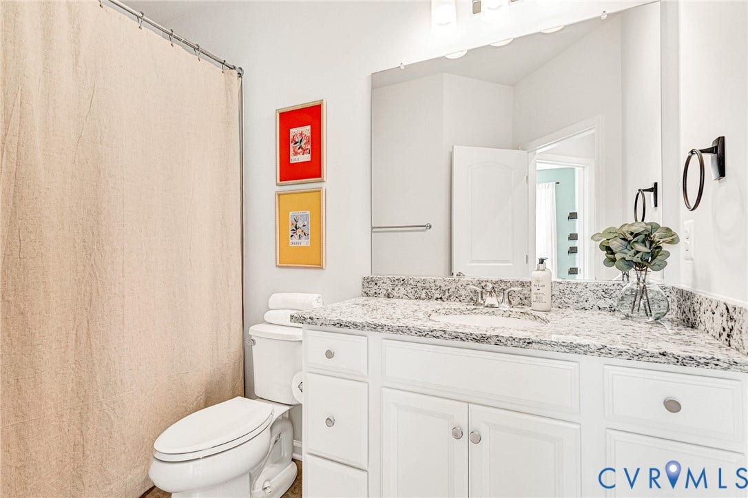 White vanity with granite countertop, integrated sink, brushed nickel faucet, and a large wall mirror