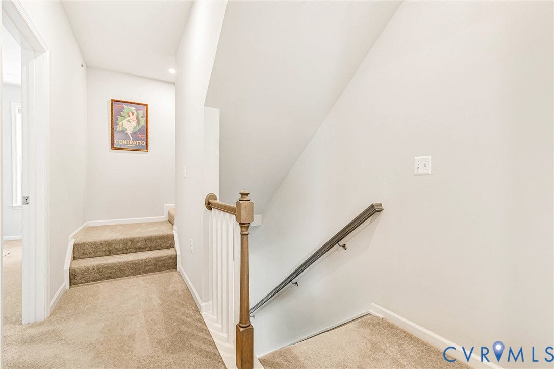 Carpeted staircase with a wood-finish newel post and a dark-finish handrail
