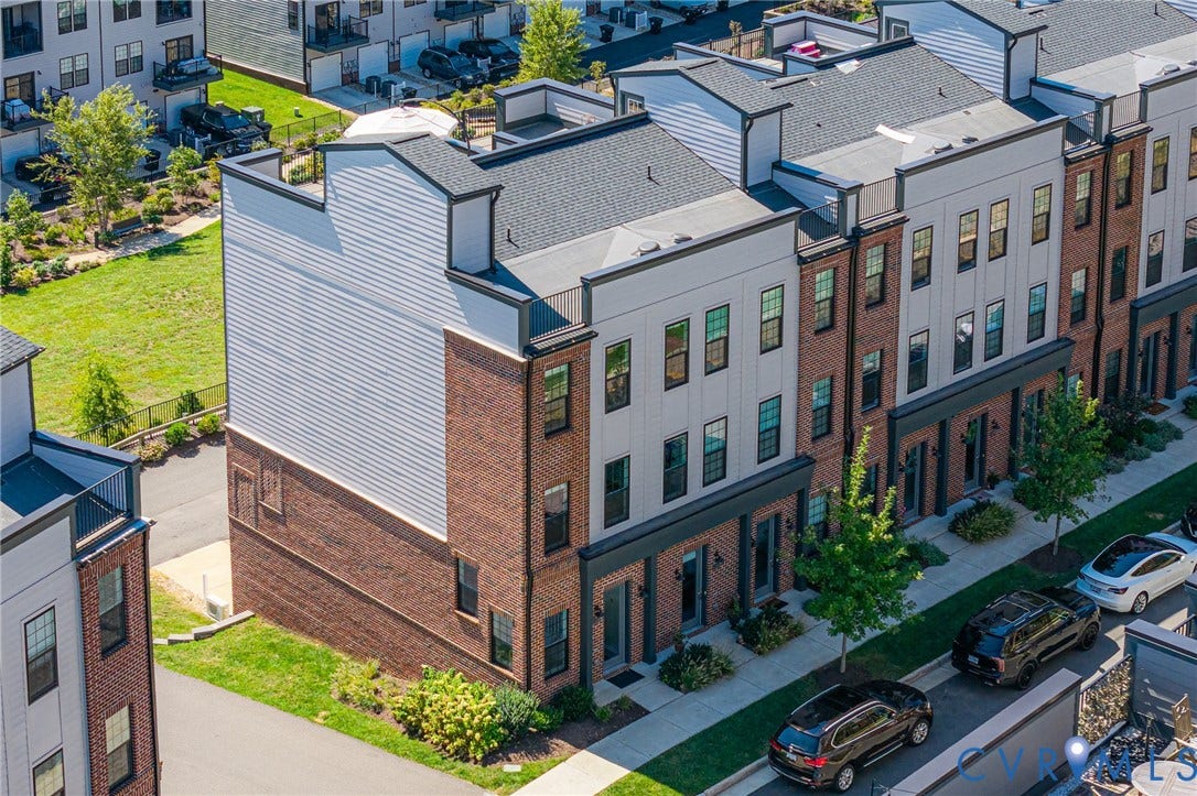Multi-level townhome featuring brick and siding facade with a dark gray roofline