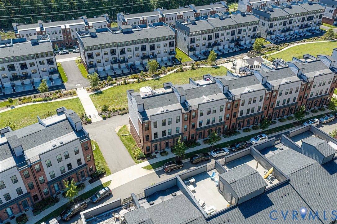 Modern townhome community featuring multi-story residences with integrated garages, private patios, and common green spaces
