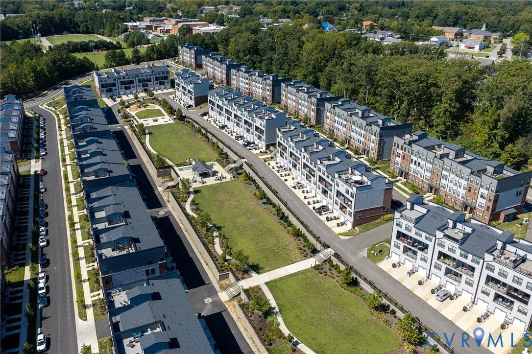 Modern townhome community featuring multiple buildings, manicured green spaces, paved roadways, and integrated pedestrian pathways