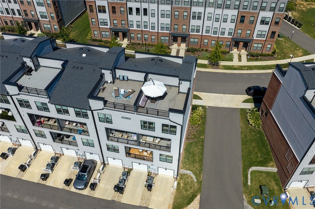 Townhome exterior featuring multiple balconies, a rooftop deck, and individual garage access