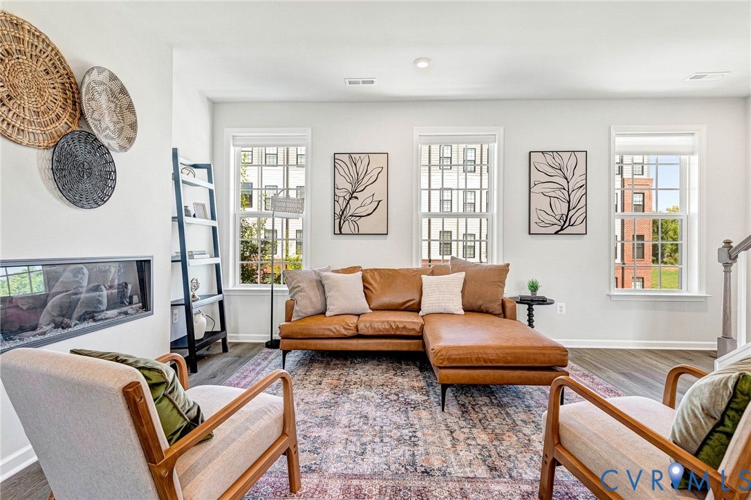 Modern linear fireplace, light-toned walls, wood-finish flooring, multiple windows, and a staircase with a wood handrail