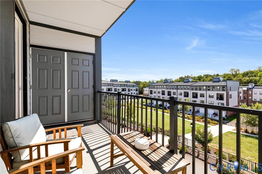 Balcony with a black metal railing, concrete flooring, and double panel doors