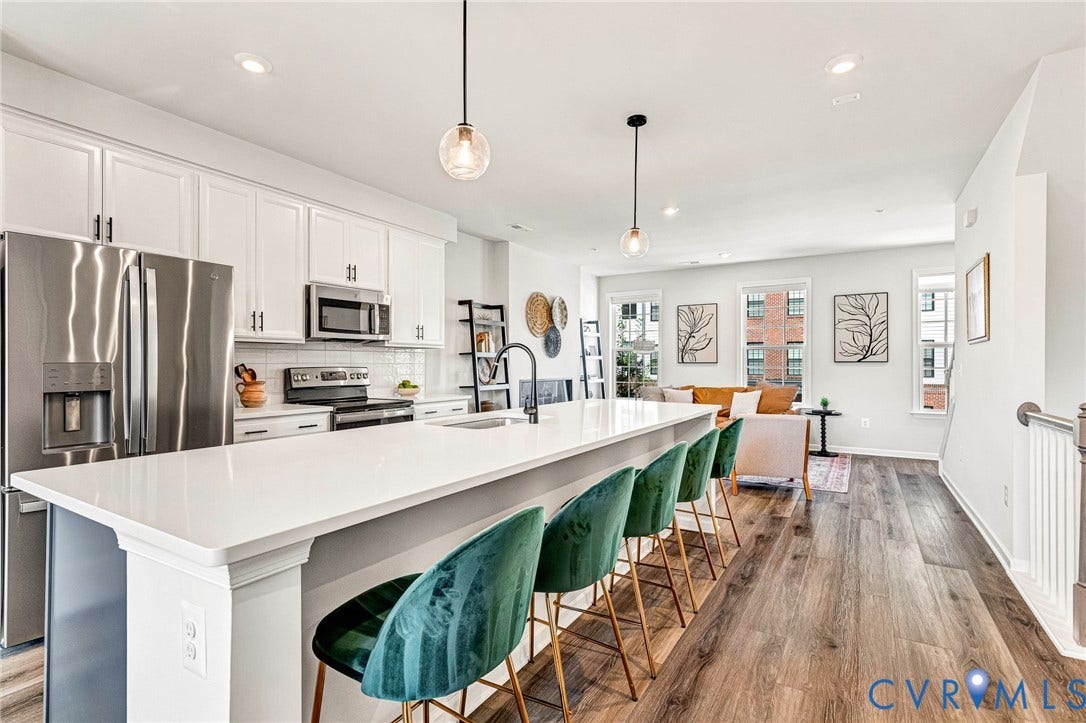 White shaker-style cabinetry, stainless steel appliances, a center island with a white countertop, and wood-finish flooring