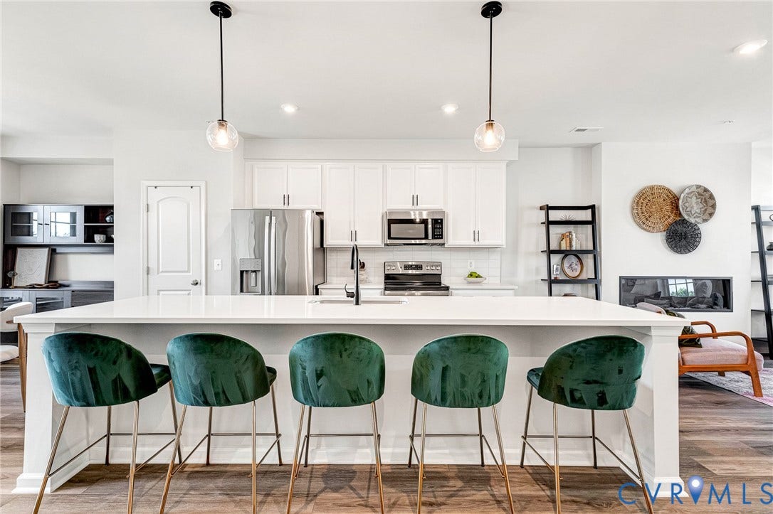 Kitchen island with white countertop, recessed lighting, wood-finish flooring, white cabinetry, and stainless steel appliances