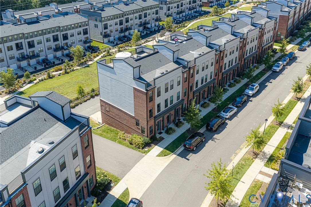 Multi-level townhome featuring brick and siding facade, individual entrances, and a sidewalk-lined street