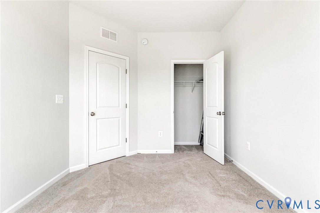 Neutral wall paint, light-toned carpeting, white interior doors, and built-in closet shelving