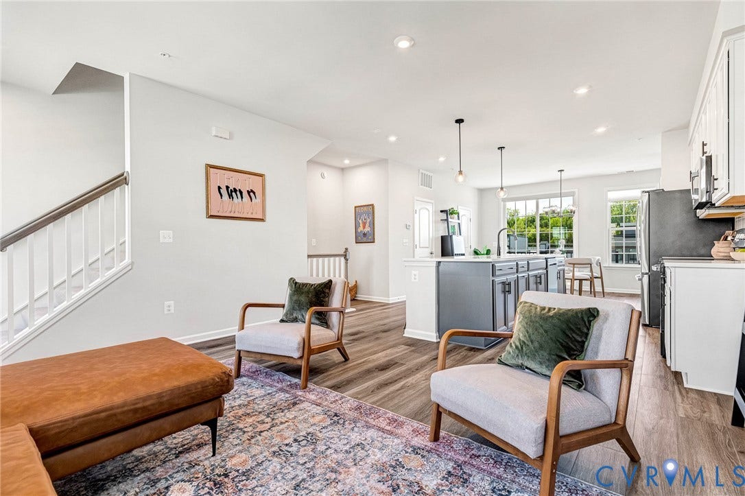 Open-concept living area featuring wood-finish flooring, recessed lighting, and a staircase with a white baluster and dark wood handrail