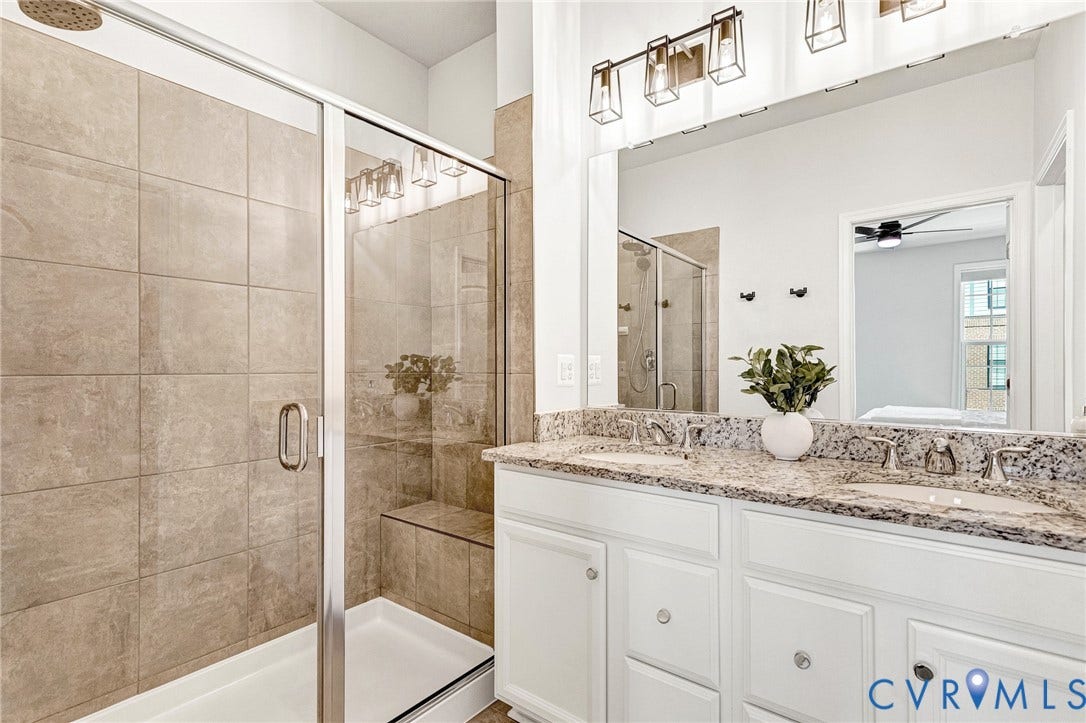 Dual vanity with stone countertop, white cabinetry, and brushed nickel fixtures