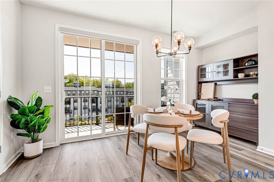 Wood-finish flooring throughout, sliding glass doors providing access to a private balcony, contemporary chandelier with clear glass globes, built-in cabinetry with glass-front uppers, and a separate single window