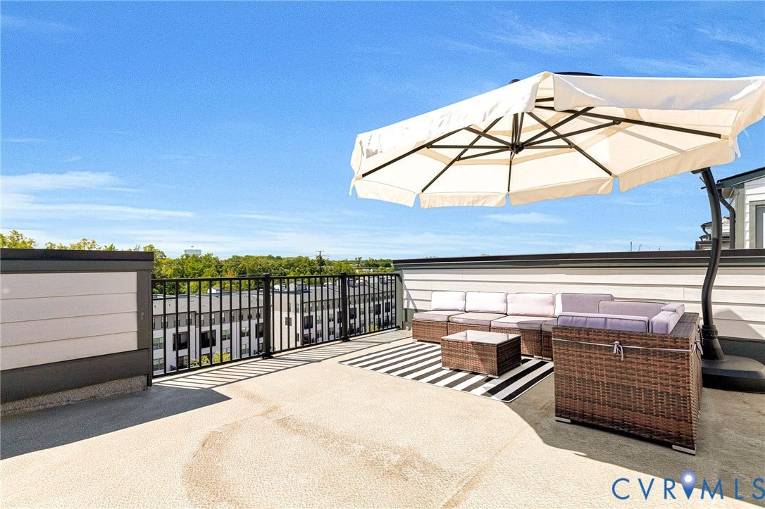 Rooftop terrace with black metal railings, composite siding accents, and a wide-plank wall